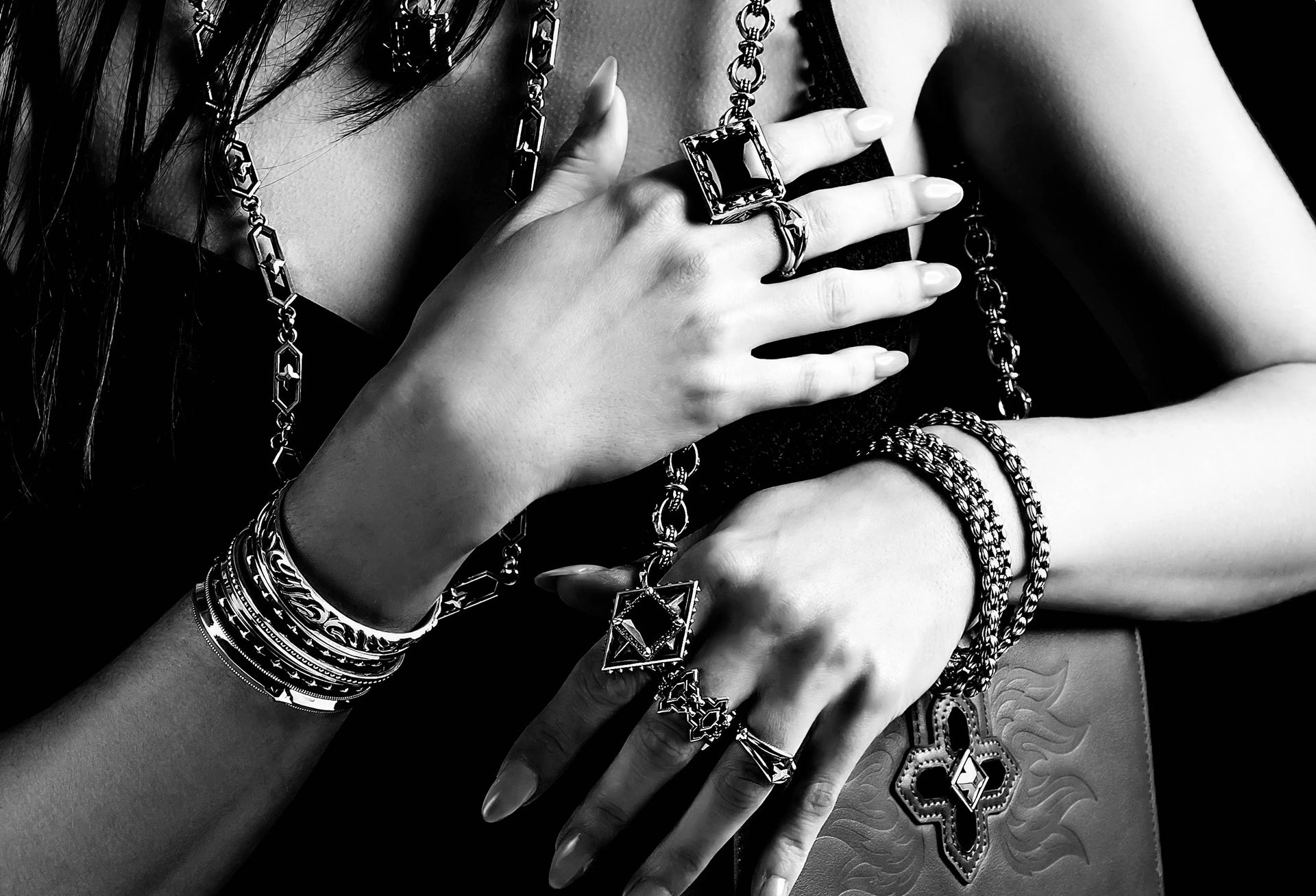 Black and white close up shot of a woman's torso and arms decorated in jewelry
